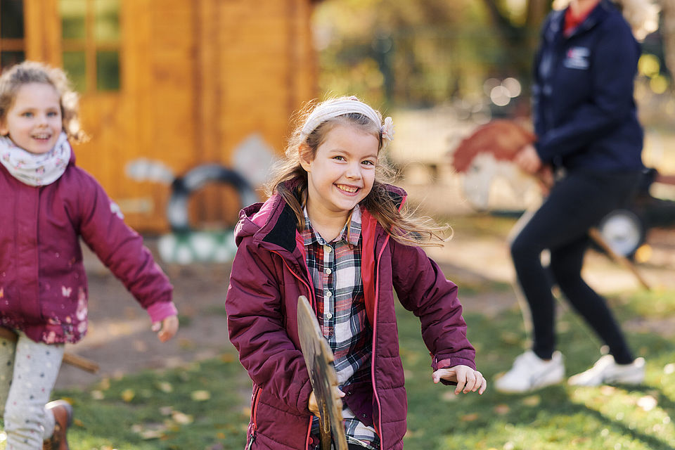 DRK - KiTa Ideenreich in Ludwigsfelde / Brandenburg: Mädchen mit einem Steckenpferd im Garten der KiTa